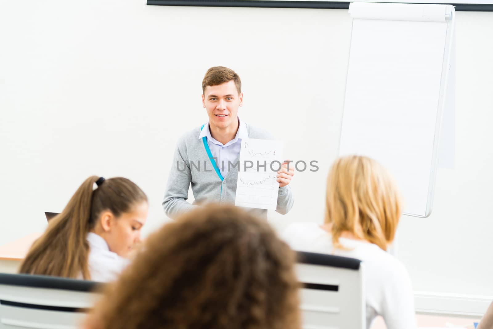 young teacher man talking with students in the classroom