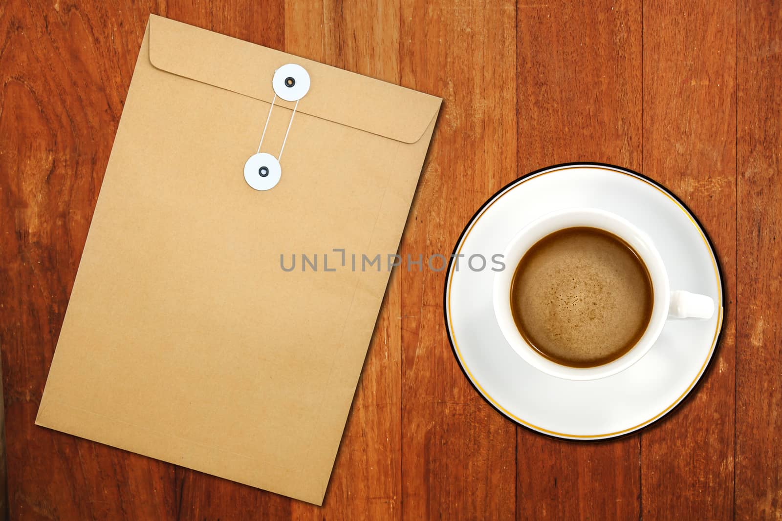 Brown Envelope document and a white coffee cup on a wooden desk