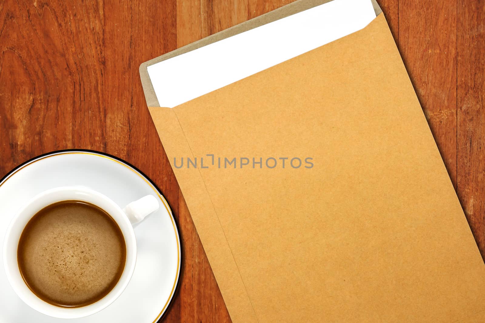 Brown Envelope document and a white coffee cup on a wooden desk