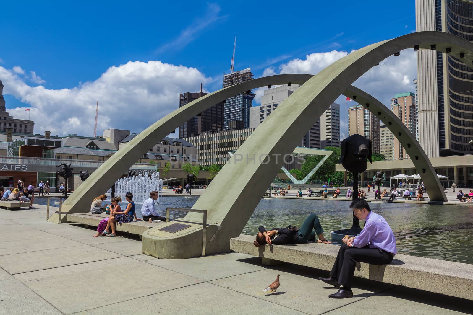 Many poeple sitting near a fountain in downtown Toronto city, Ontario, Canada.