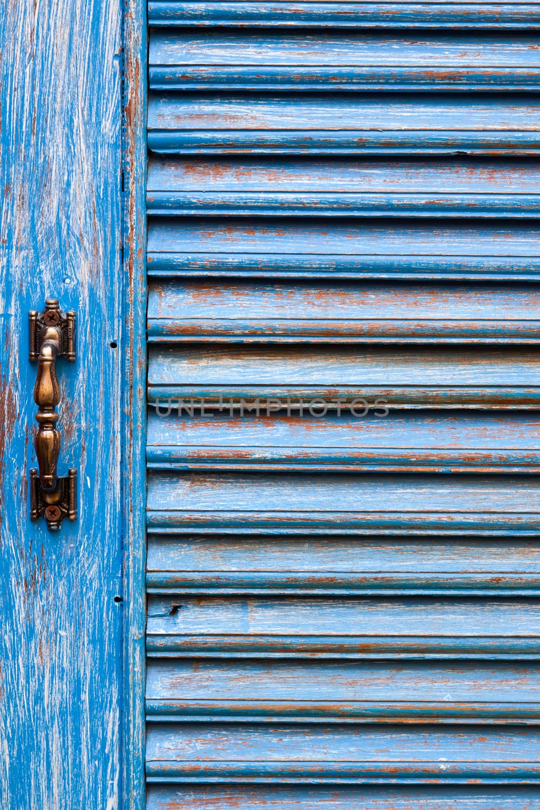 Door handles with an old wood door painted with blue