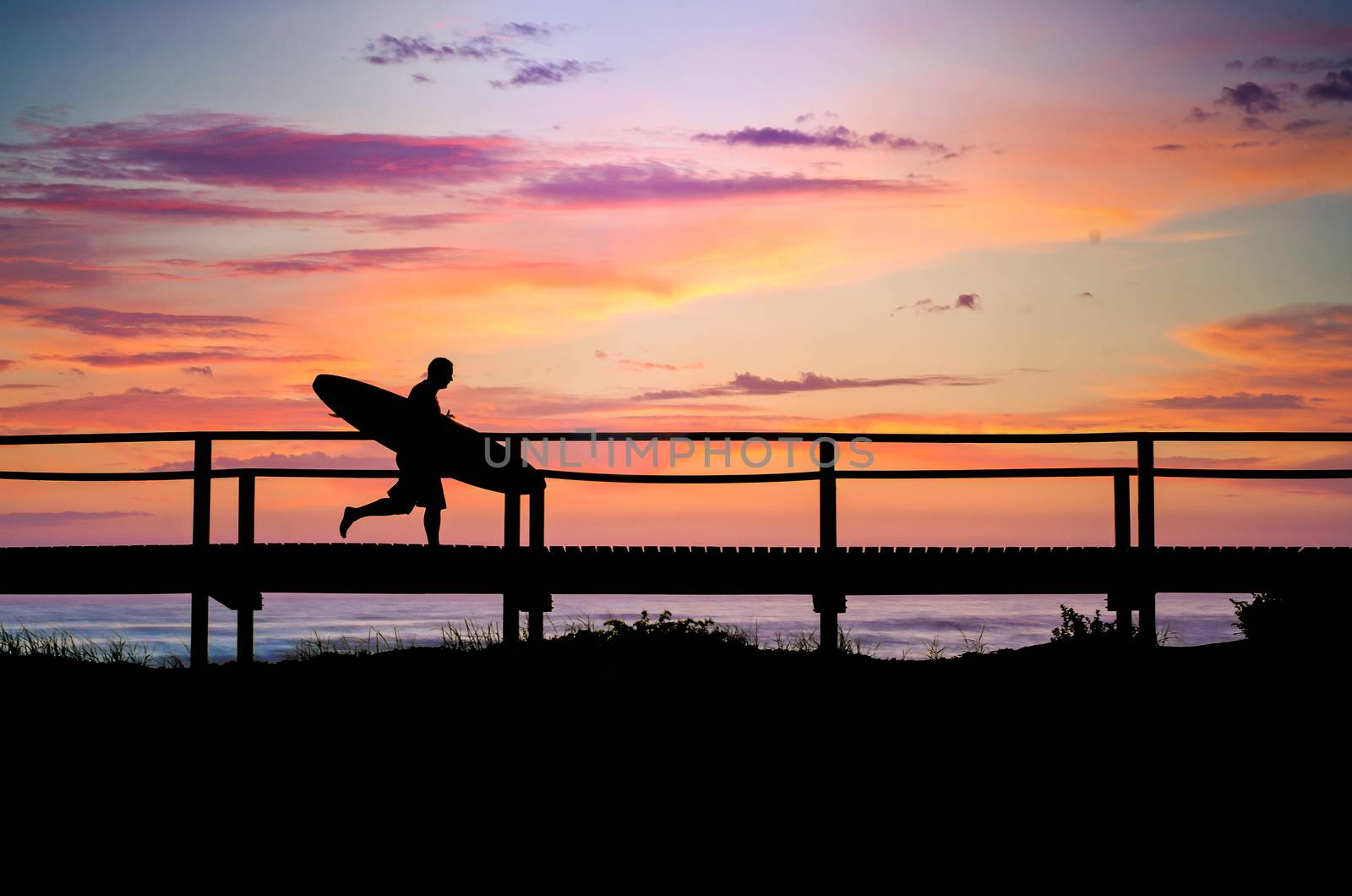 A surfer running to the beach at sunset in Portugal.