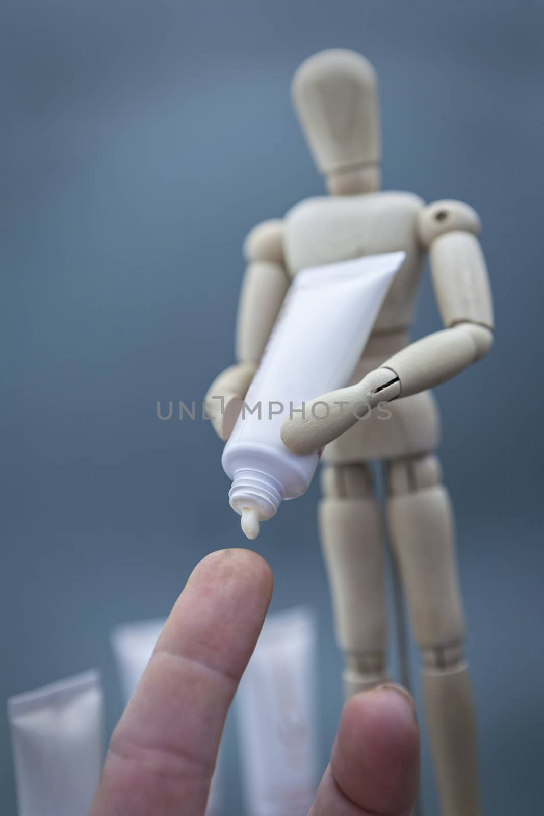 Articulated wooden doll with packing cremates dispenses cream on by digicomphoto