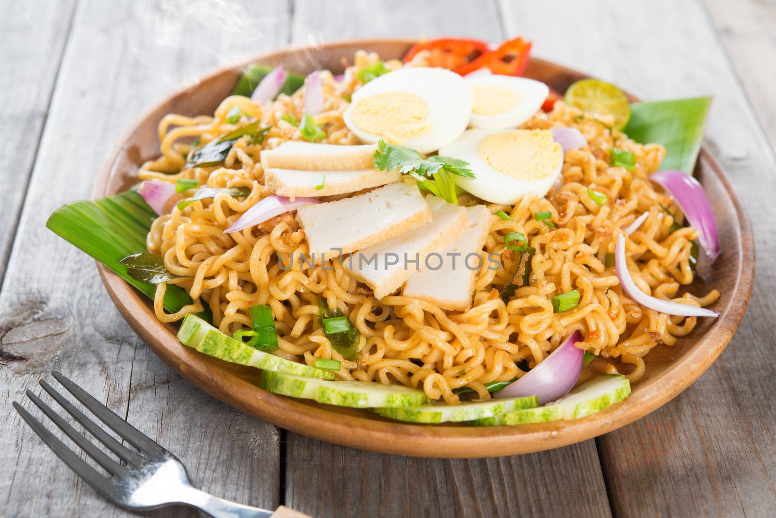 Dry Instant Noodle, Malaysian style maggi goreng mamak or spicy dry curry instant noodles. Asian cuisine, ready to serve on wooden dining table setting. Fresh hot with steamed smoke.