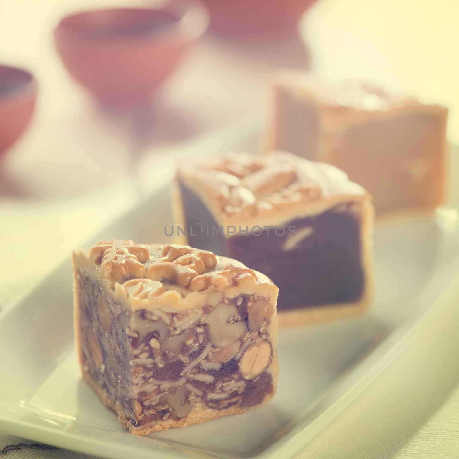 Retro vintage style Chinese mid autumn festival foods. Traditional mooncakes on table setting with teacup. The Chinese words on the mooncakes means assorted fruits nuts, not a logo or trademark.