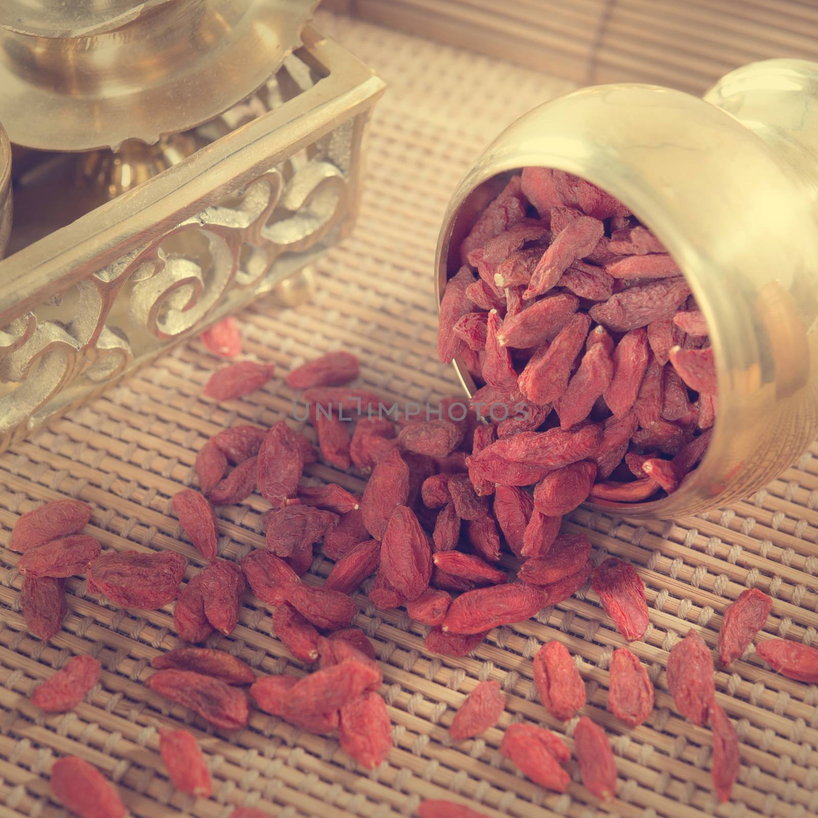 Vintage retra style red dried goji berries, wolfberry or lycium, chinese herbal medicine close-up on bamboo mat. Lycium barbarum.