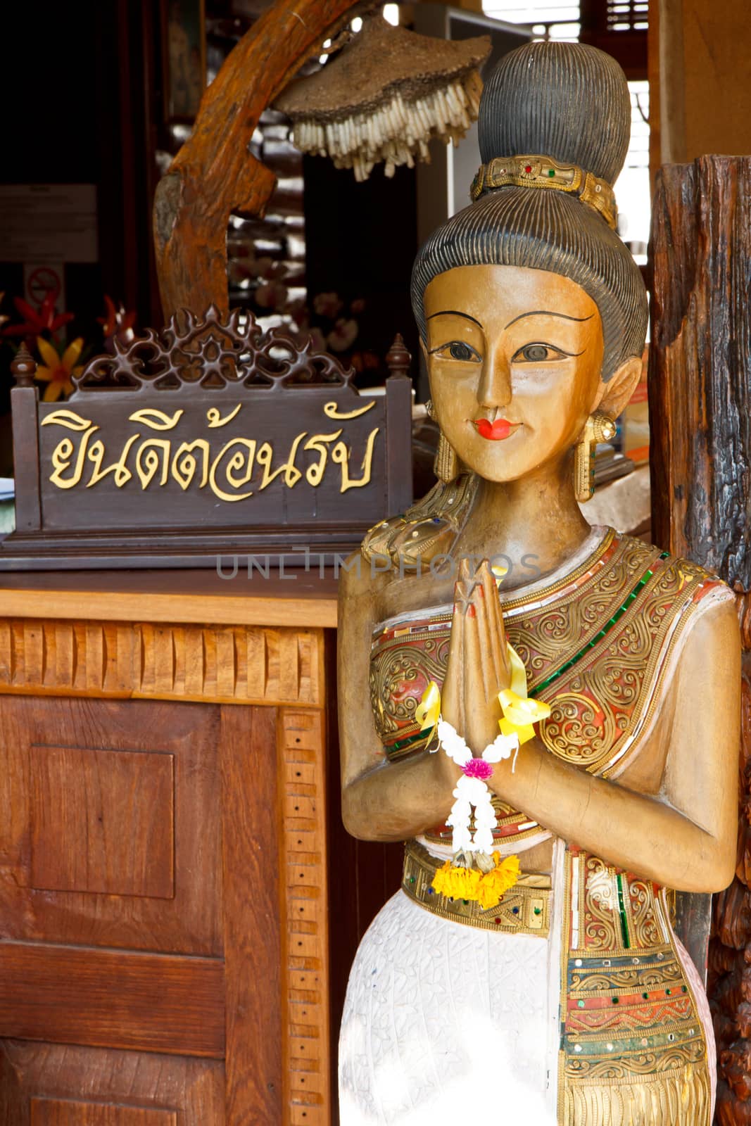 You're welcome in thai word on wood piece with Thai woman sculpture for Sawasdee welcome of thailand