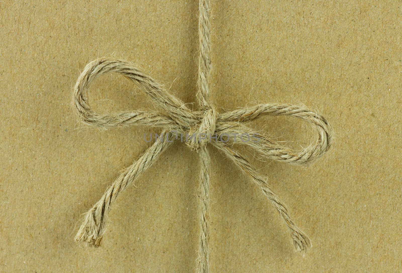 String tied in a bow, over brown recycled paper