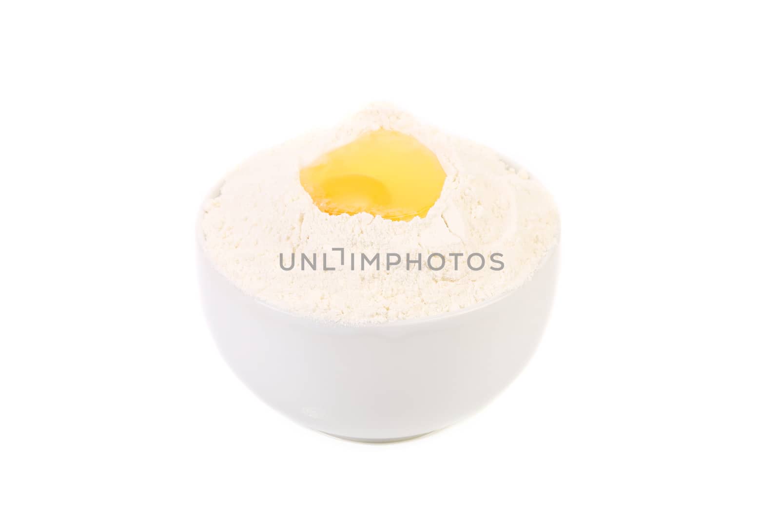Yellow raw egg yolk on flour in bowl. Isolated on a white background.