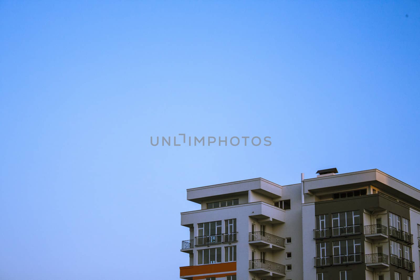 Top of new devoid of inhabitants building and blue sky. There is space for text.