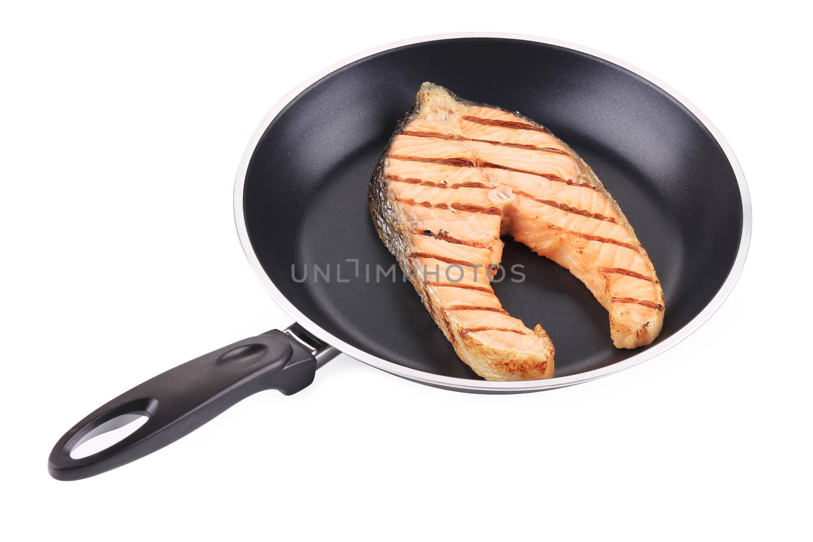 Salmon steak on a black frying pan. Isolated on a white background.