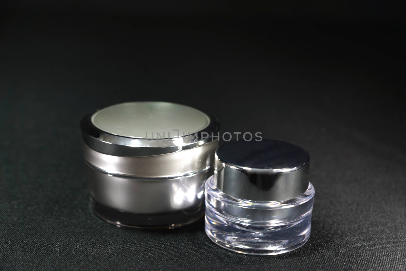 two different shaped acrylic cream pot, on black scene,shallow focus