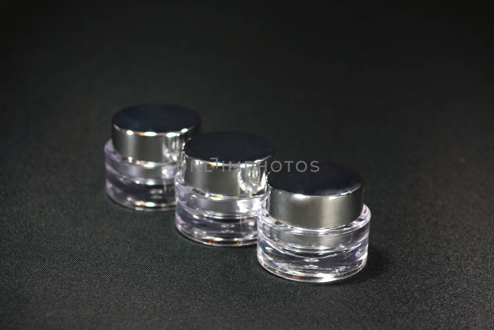 three circular shaped acrylic cream pot, on black scene,shallow focus