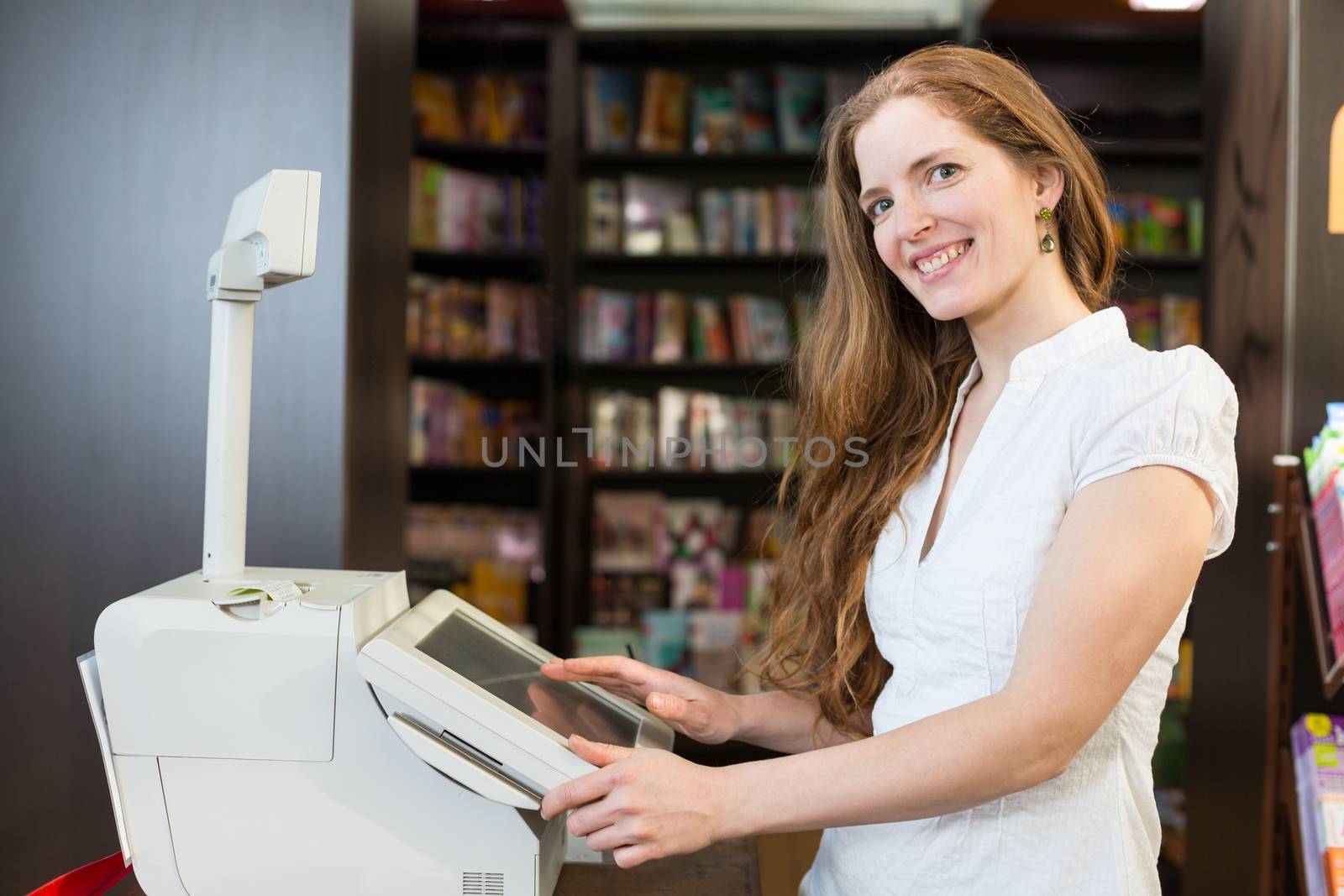 Female cashier at cash register in bookstore