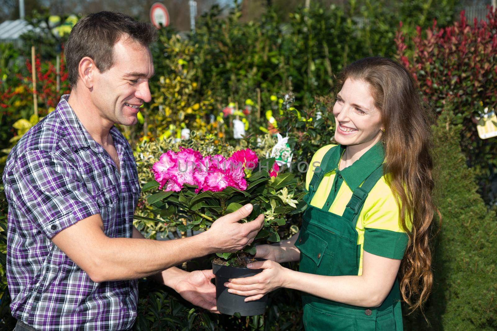 Female florist hands flower to customer in shop by ikonoklast_fotografie