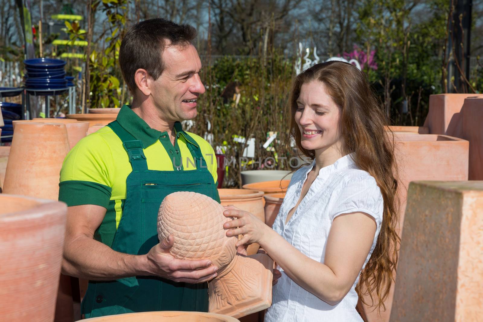 Employee in garden center selling pottery to customer or client