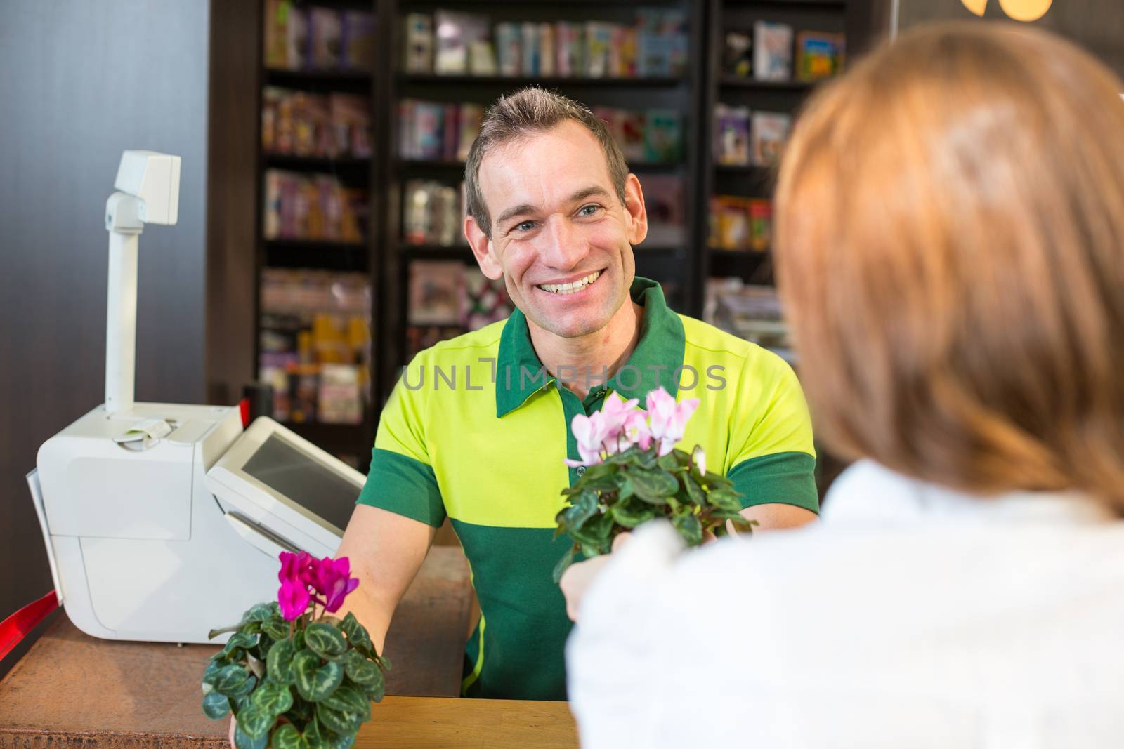 Cashier or shopkeeper in flower shop or retail store serving a customer