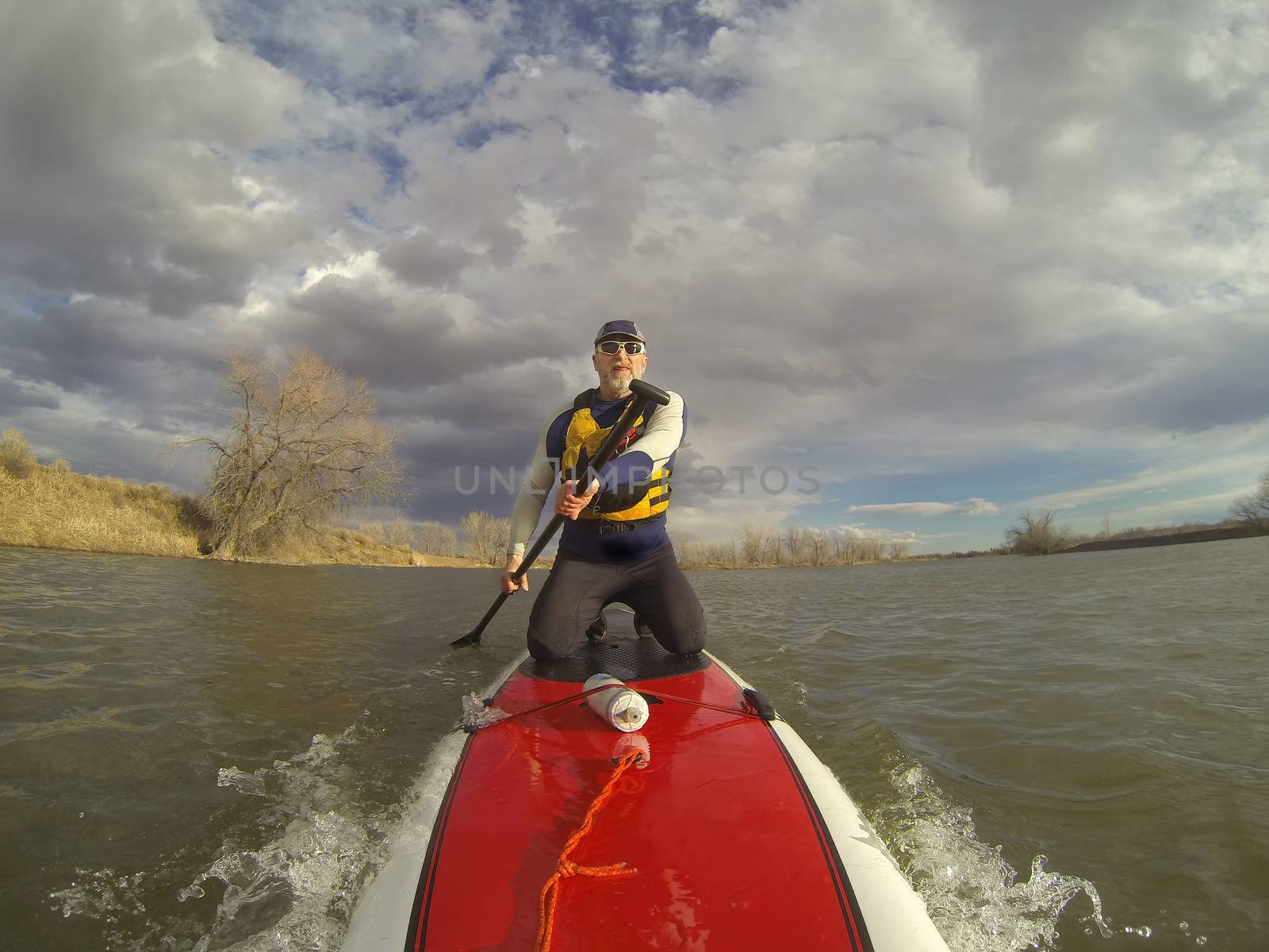 kneeling on stand up paddleboard by PixelsAway