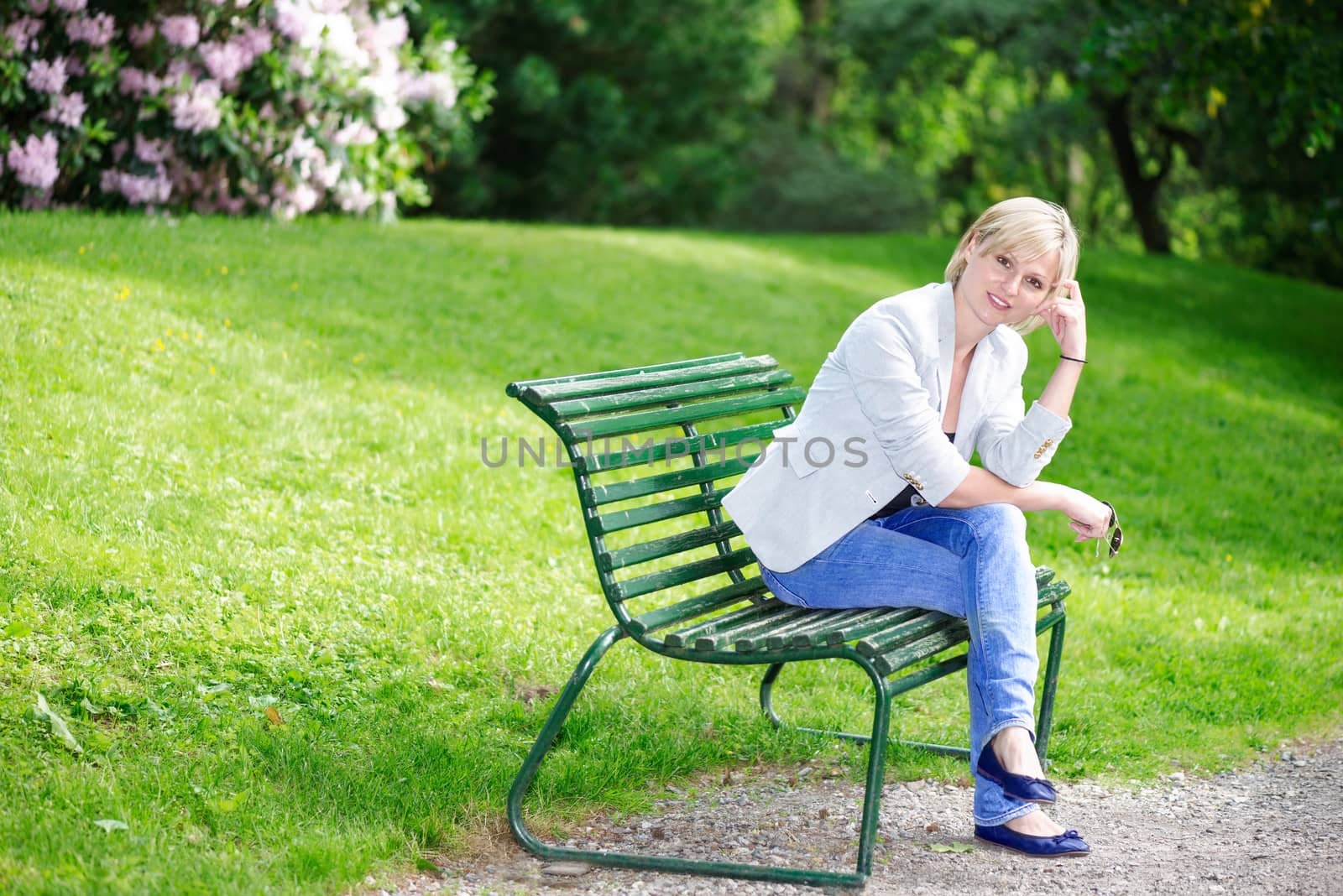 Handsome blond woman on bench looking at camera by Nanisimova