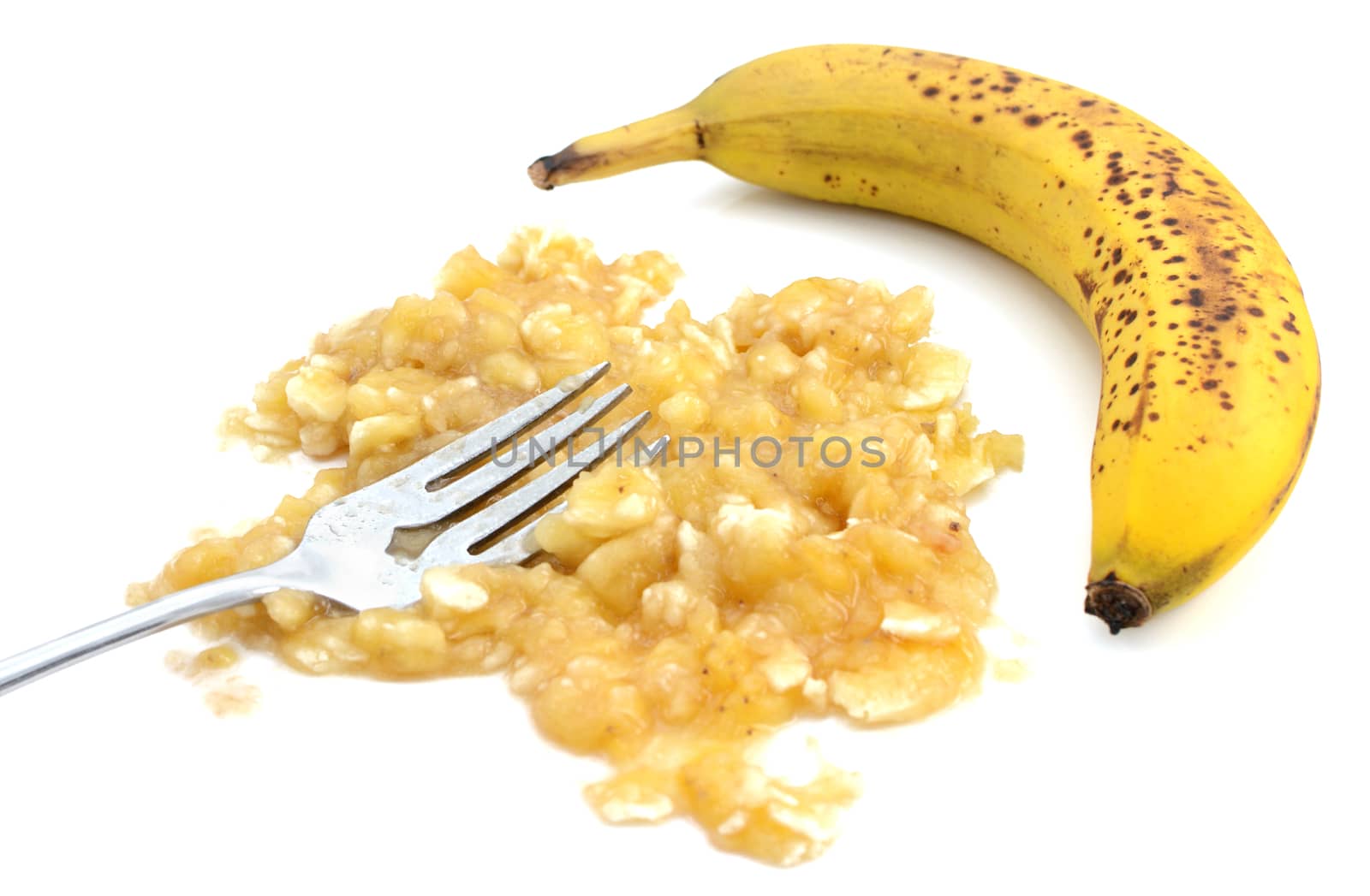 Closeup of mashed banana with fork and an unpeeled fruit, isolated on a white background