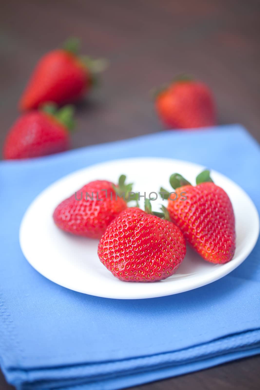 red juicy strawberry in a plate on a wooden surface