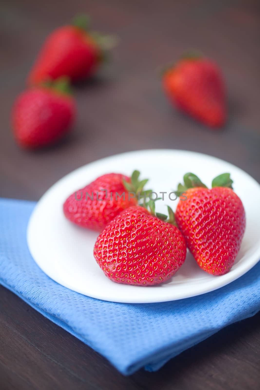 red juicy strawberry in a plate on a wooden surface