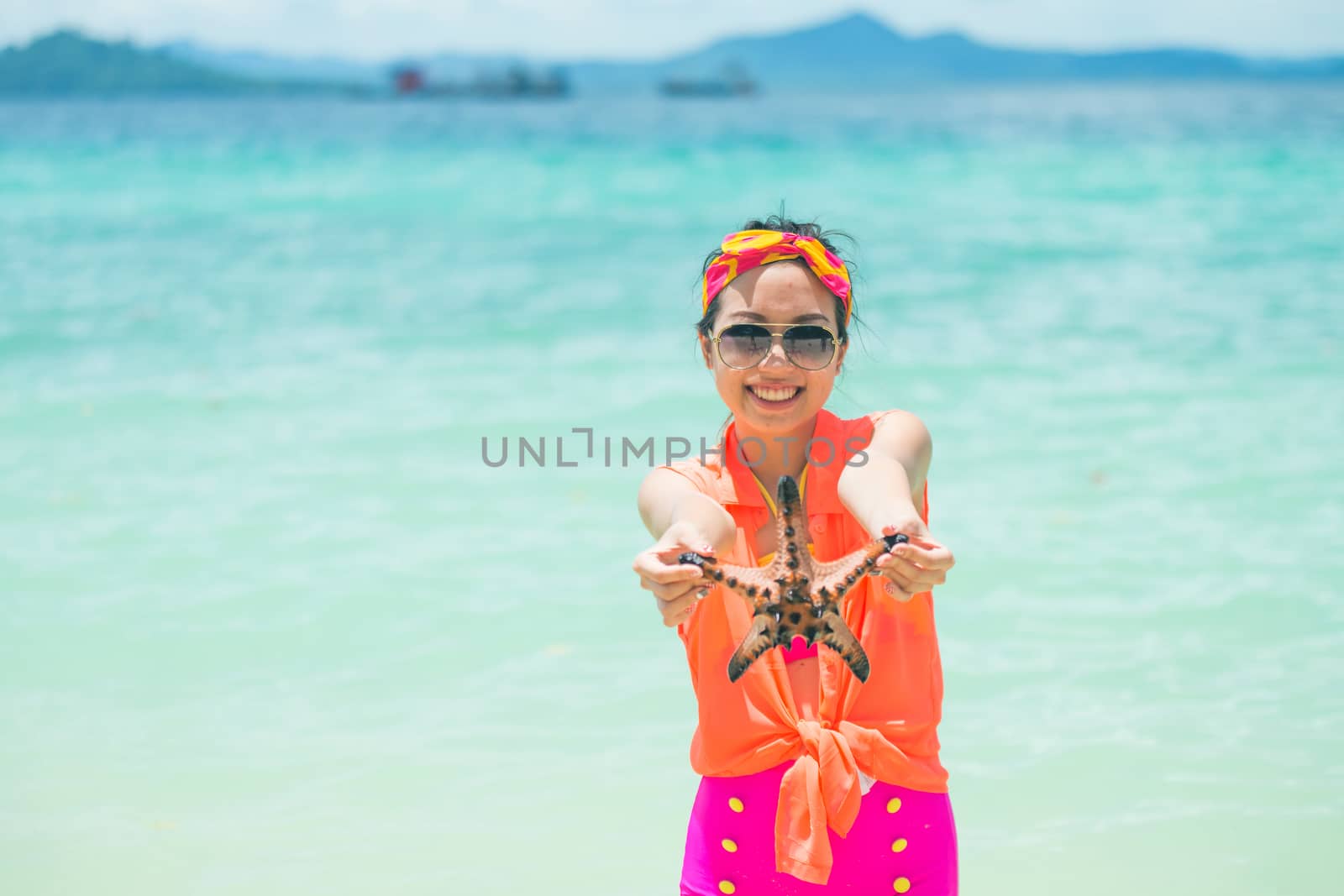 Young woman shows starfish during holiday at tropical island