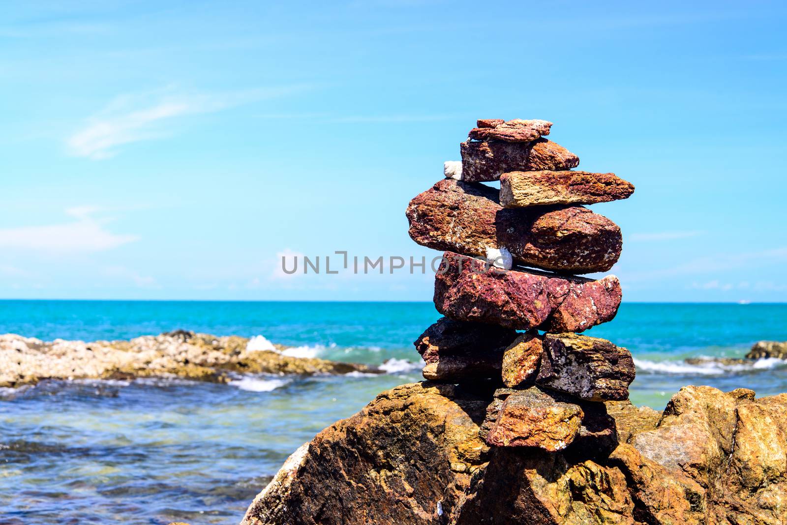 Stack of pebbles balancing on a sky background  by jakgree
