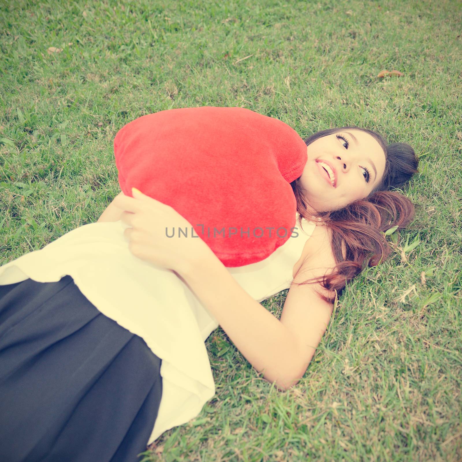 Women holding big love heart shape pillow on green grass
