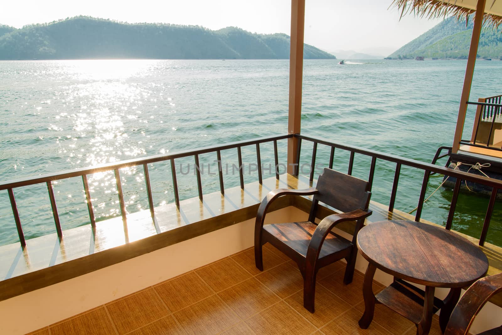 Wooden chairs on a house facing a lake with mountains background