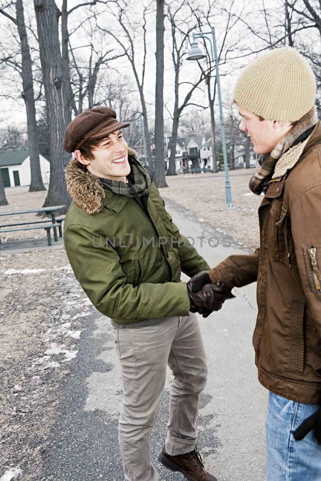 Two men shaking hands in park by elenathewise