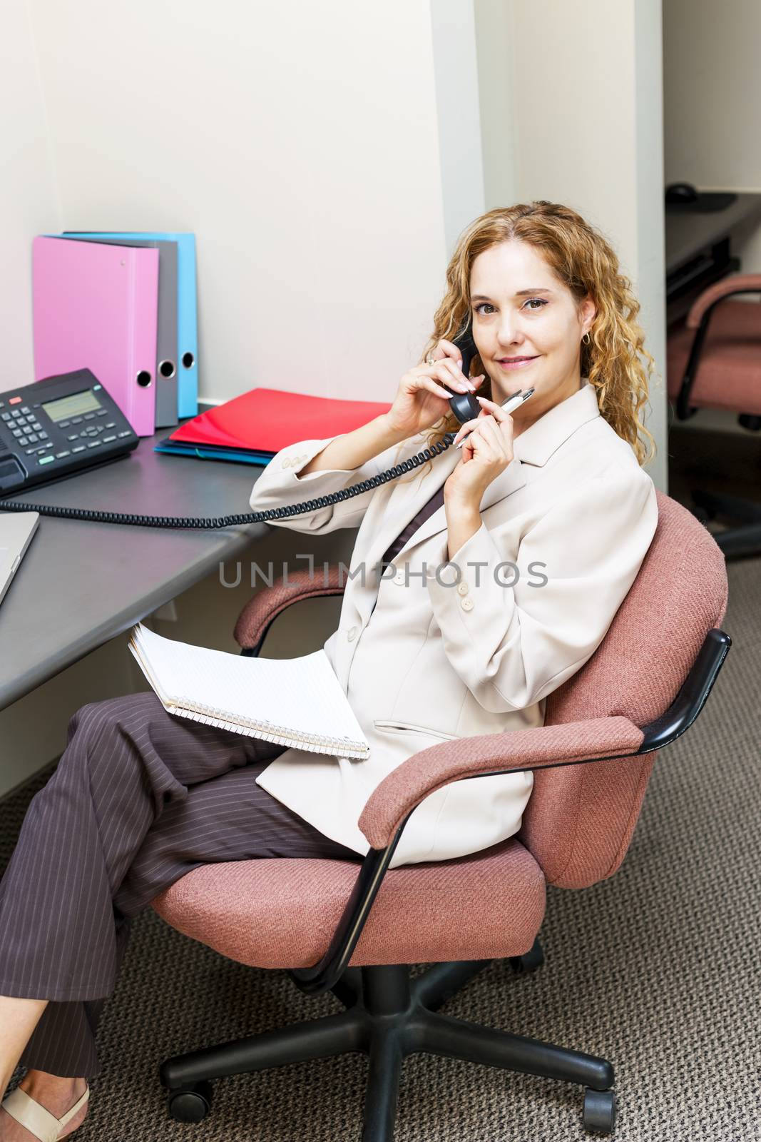 Businesswoman on telephone at office desk by elenathewise