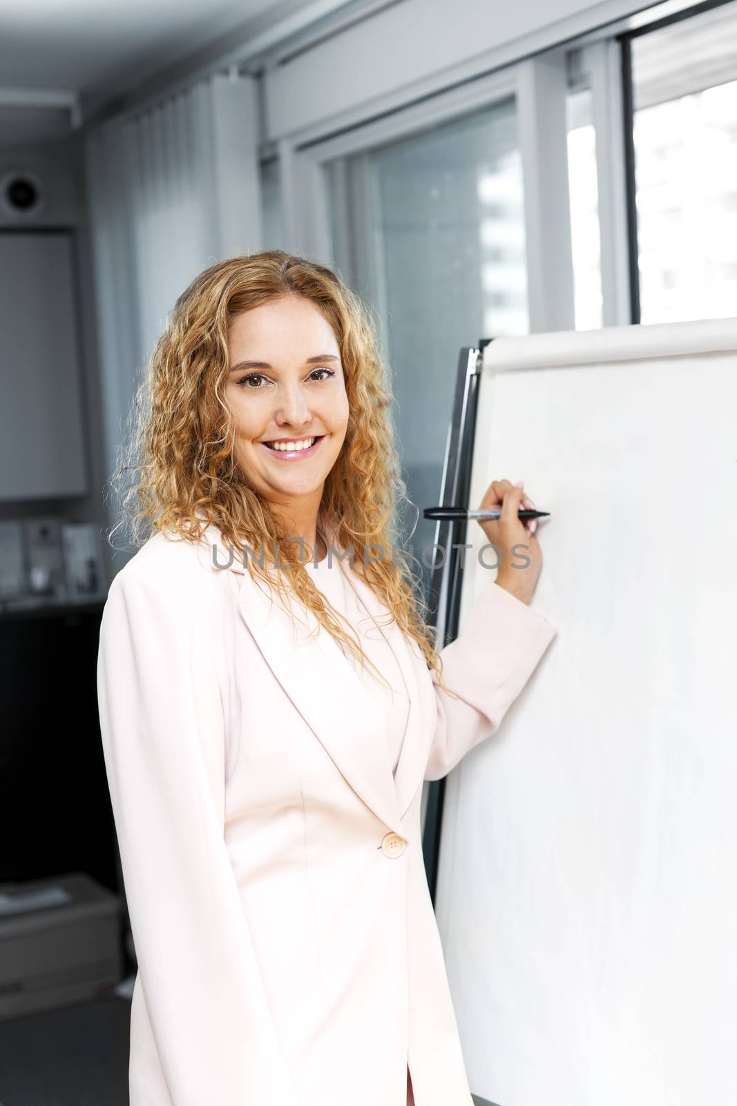 Business woman writing on flip chart by elenathewise