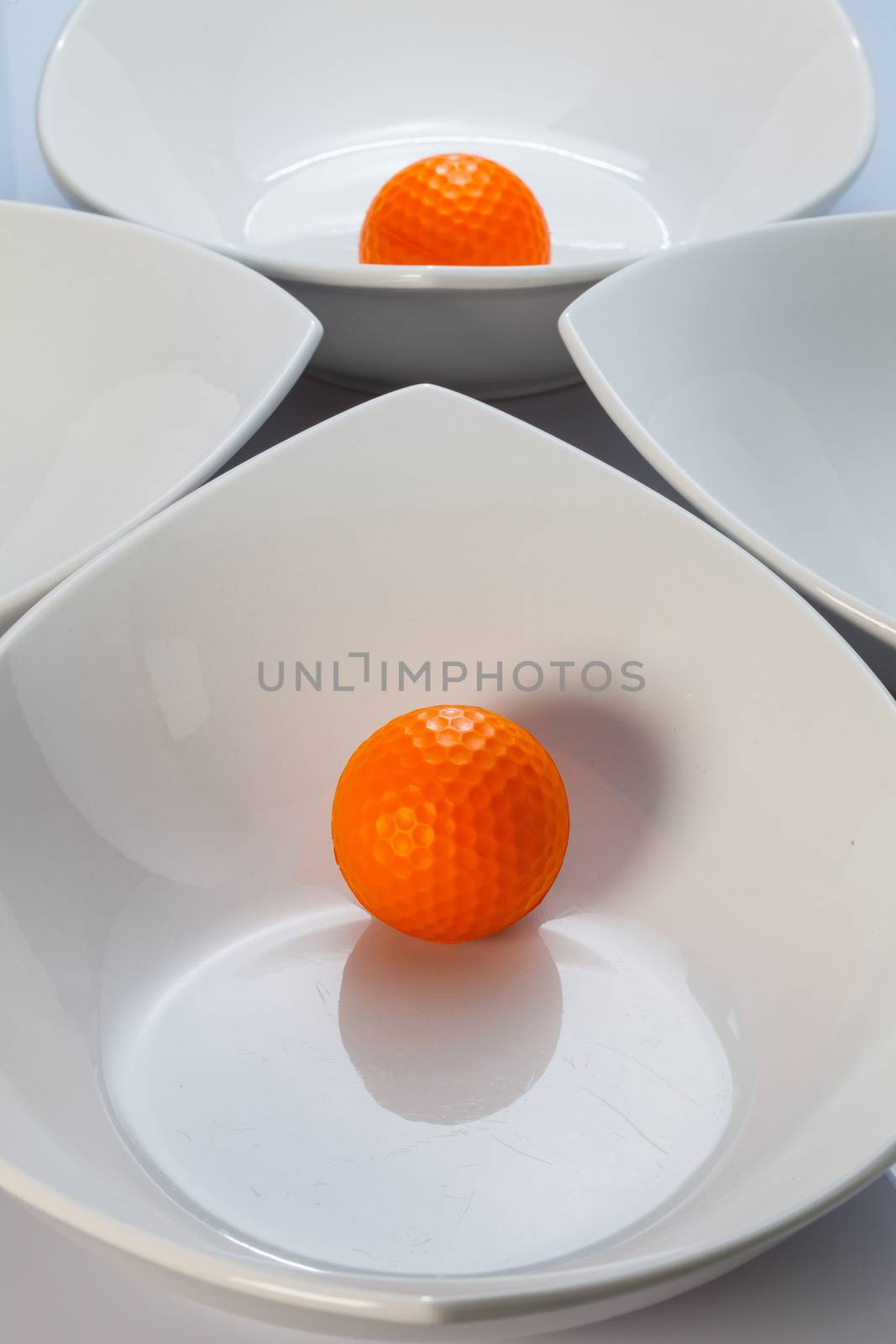 White ceramics bowls and orange golf ball by CaptureLight