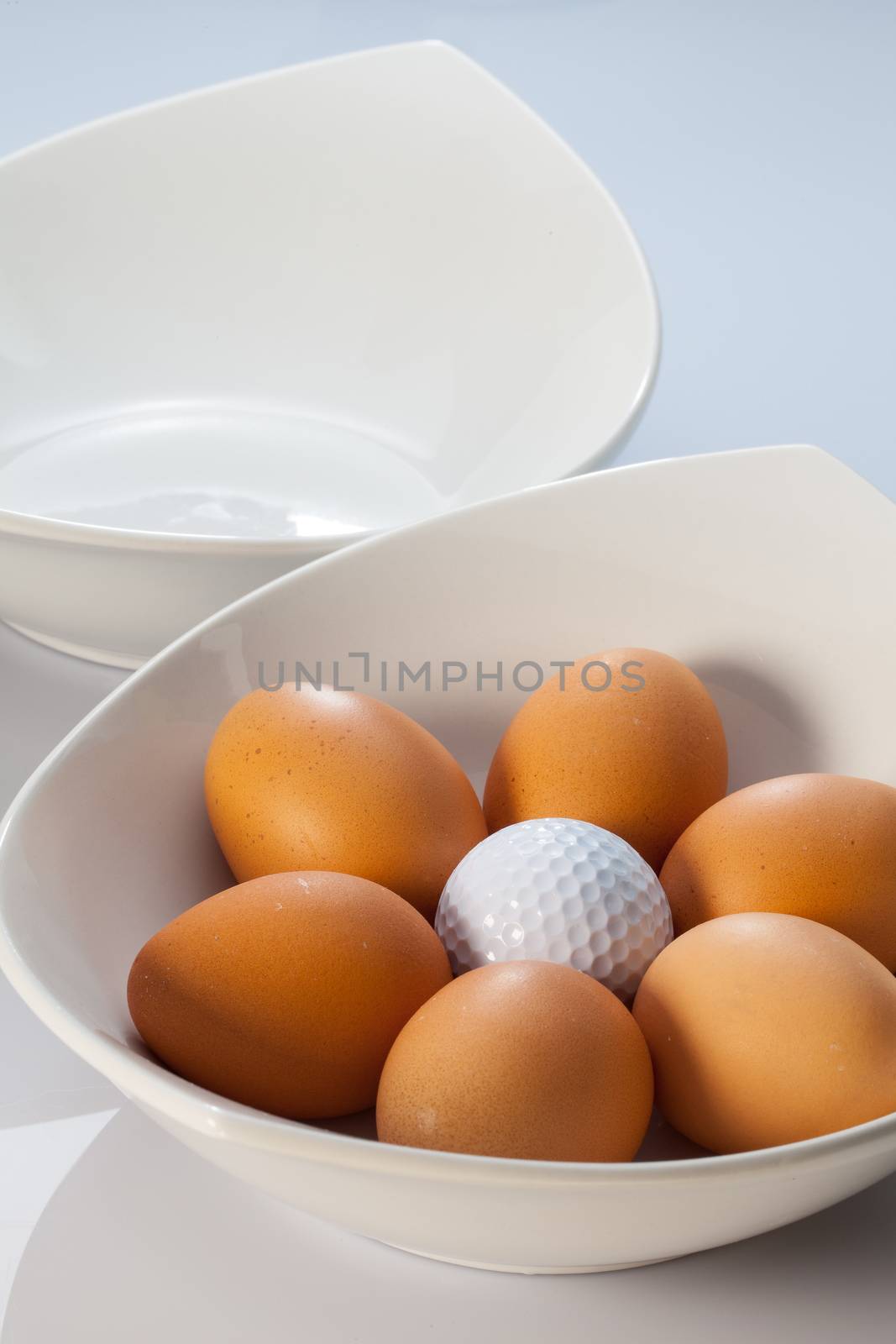Two white ceramics bowls,easter eggs and golf balls