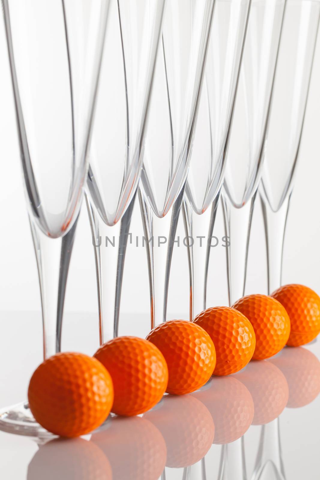 Glasses of champagne and golf equipments on a glass table by CaptureLight