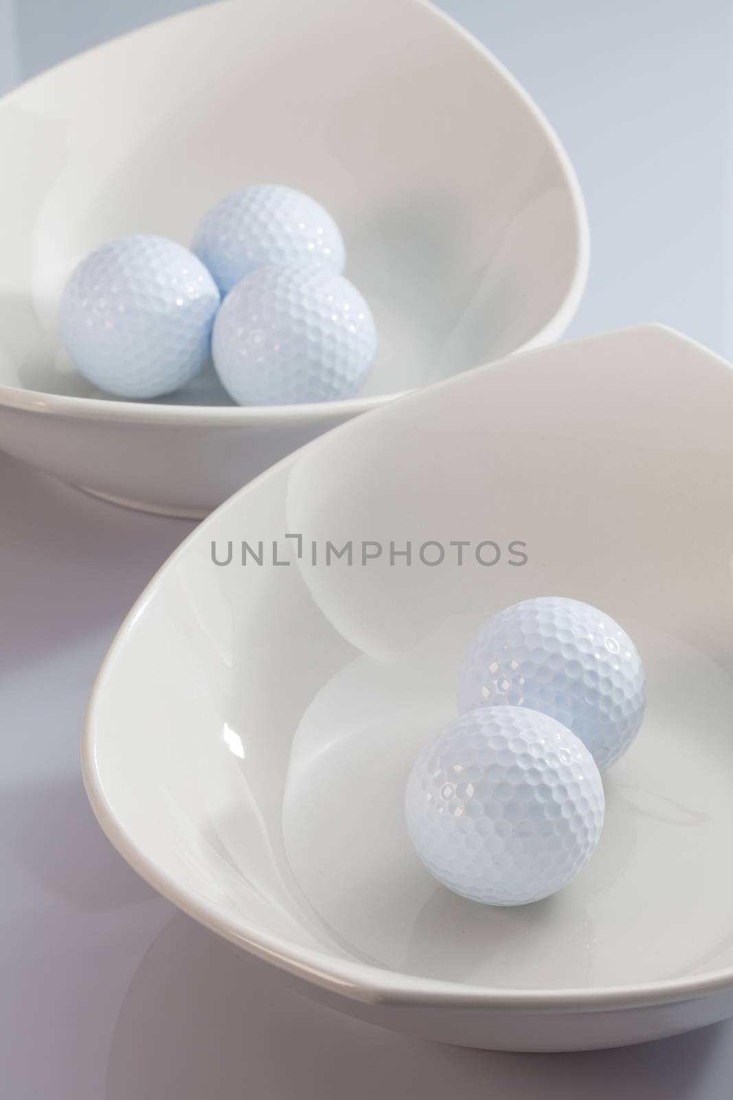 Two white ceramics bowls and golf balls