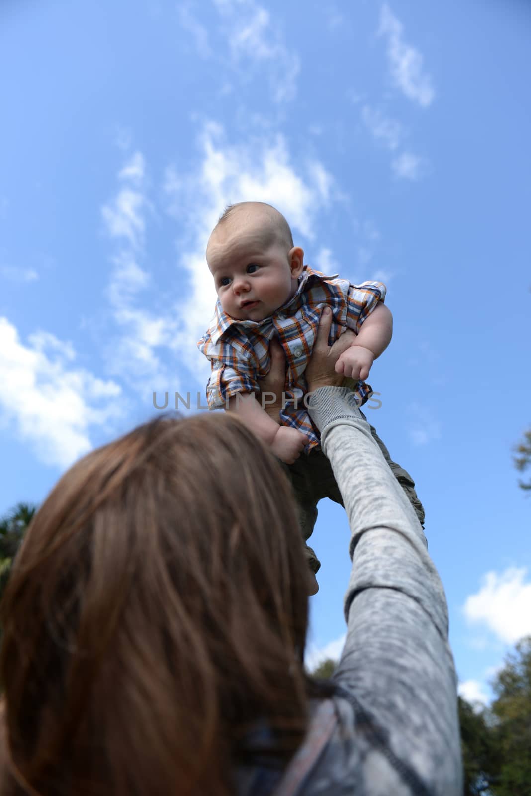 flying baby with mother holding baby against sky