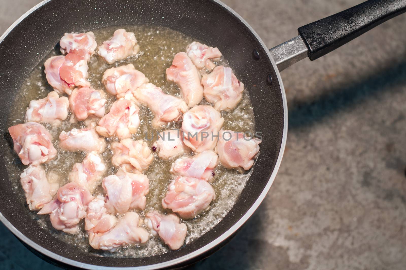 Hot cooking oil in a frying pan with chicken