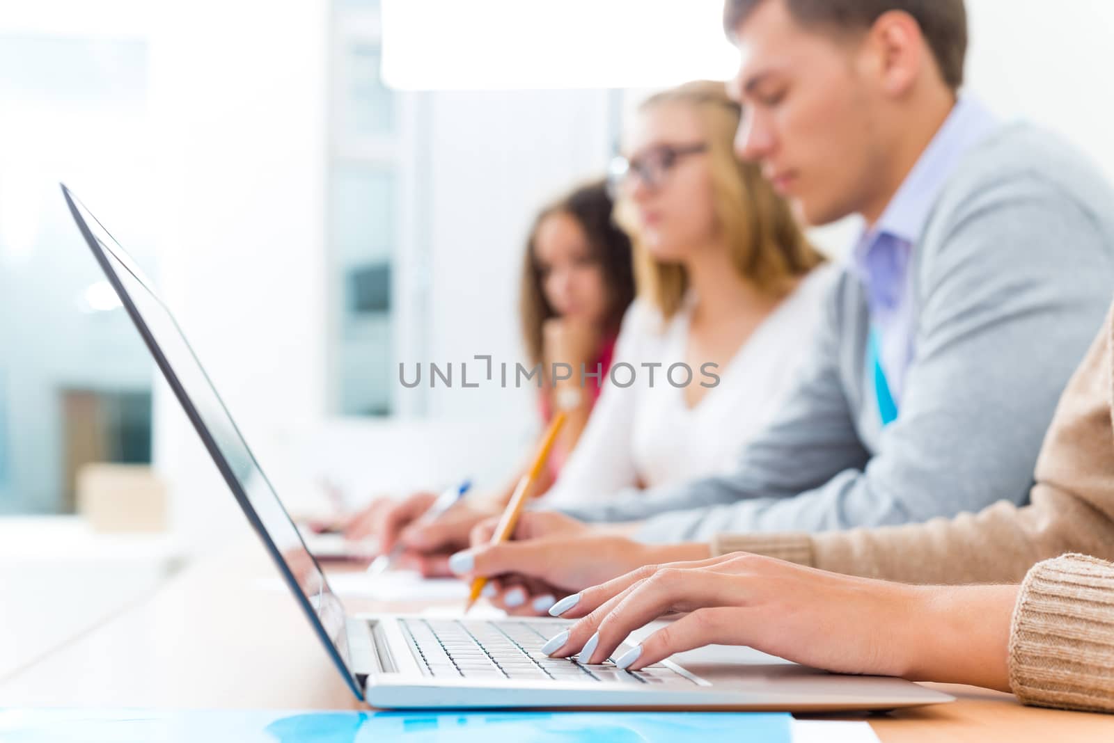 close-up of female hands on the laptop keyboard, students listen to the teacher at the University of