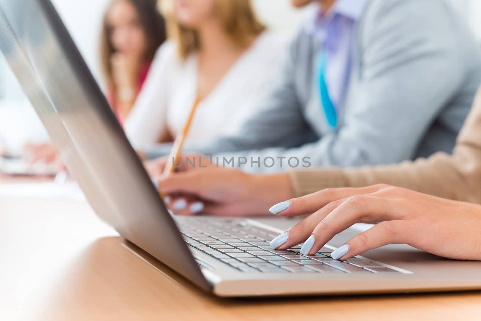 close-up of female hands on the laptop keyboard, students listen to the teacher at the University of