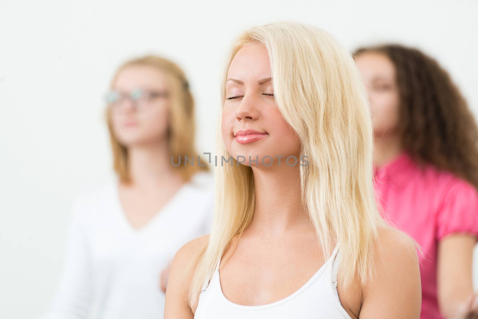 portrait of an attractive young woman, meditating with closed eyes, group meditation