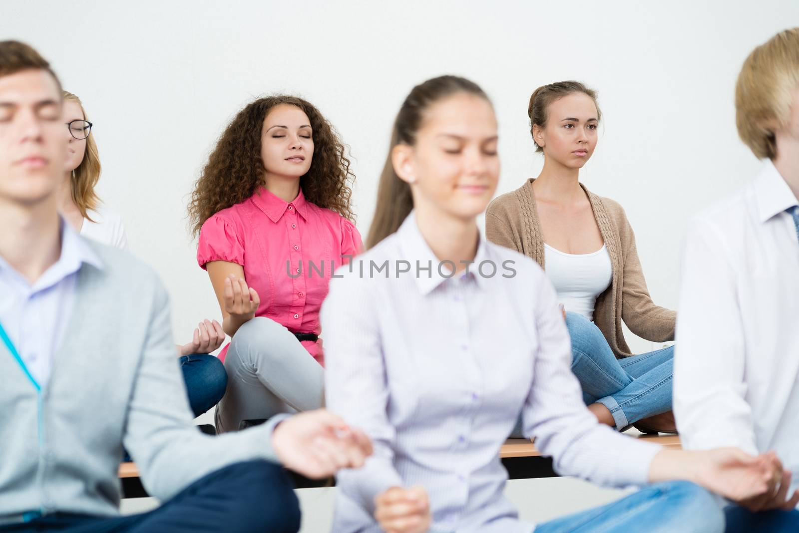 group of young people meditating in office at desk, group meditation