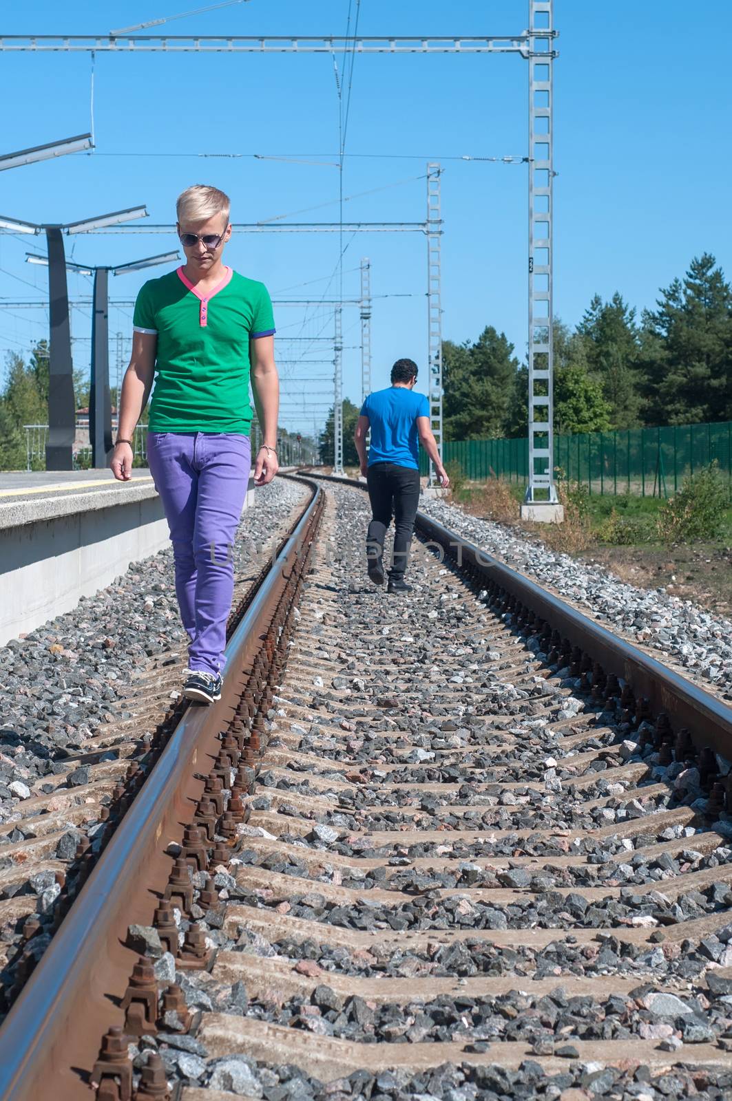 Handsome man walking on train tracks by anytka