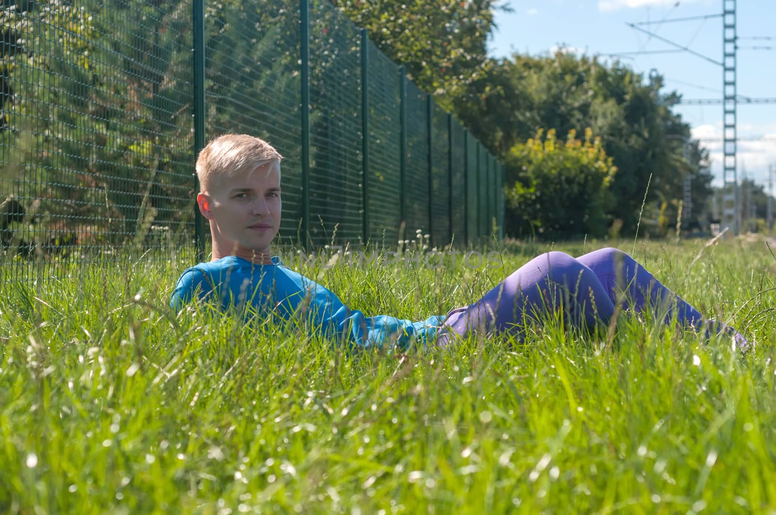 Young an in blue t-shirt lying in a grass