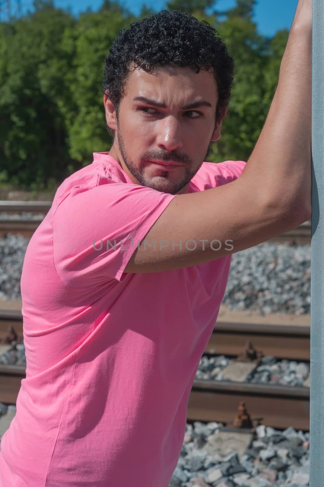 Handsome young guy in pink t-shirt watching on you