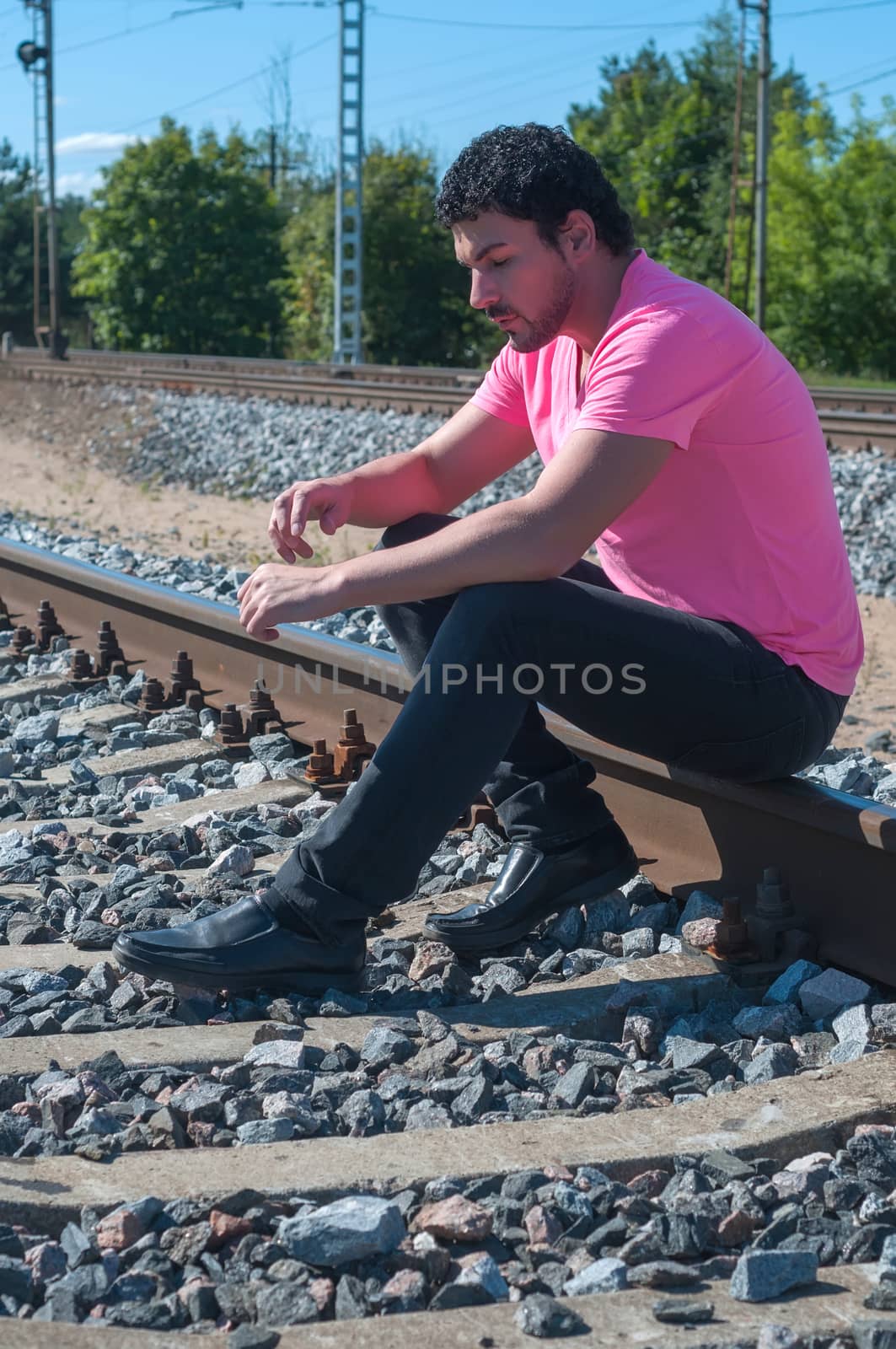 Shot of one man in pink sitting on train tracks