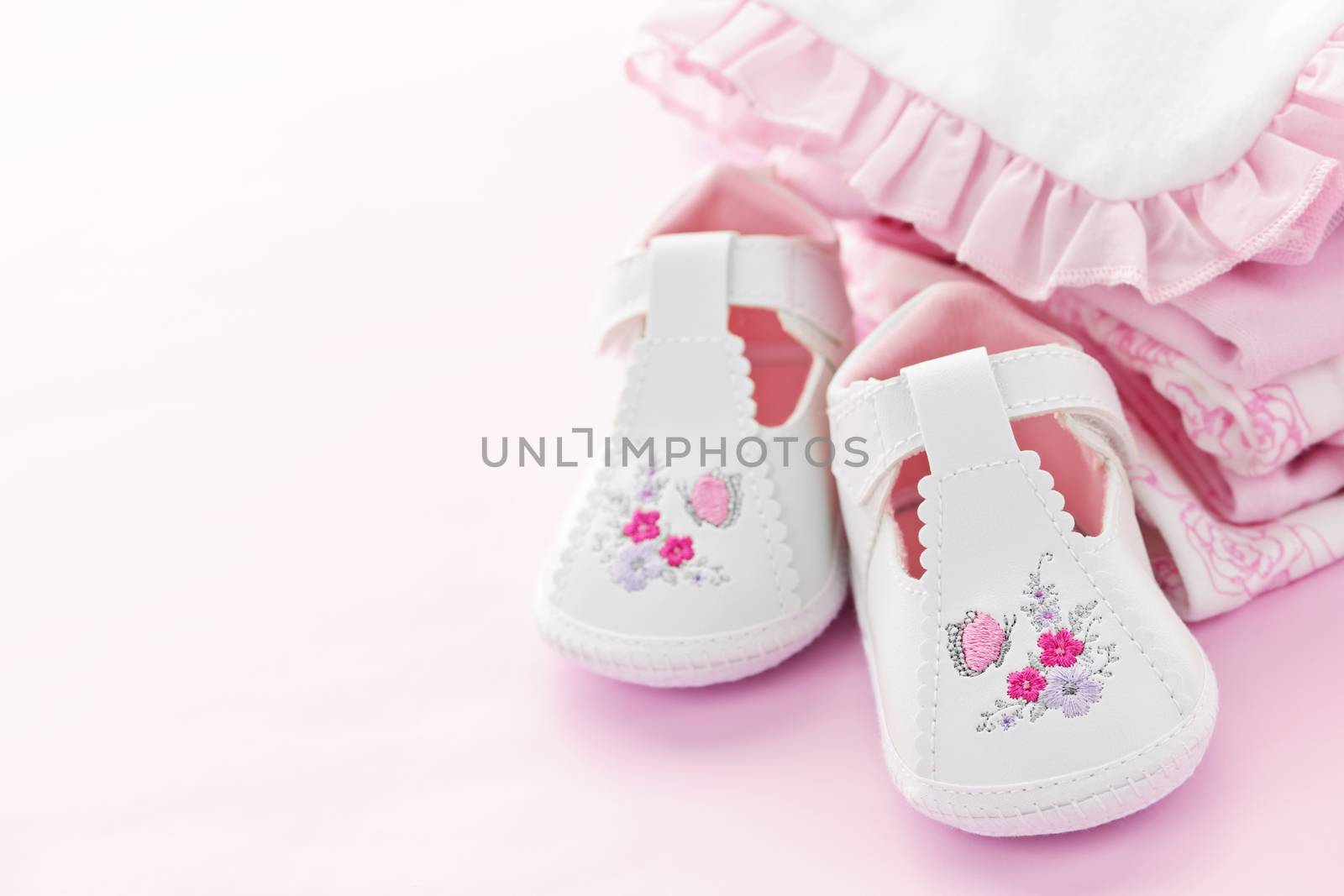 Infant girl clothing and shoes for baby shower on pink background