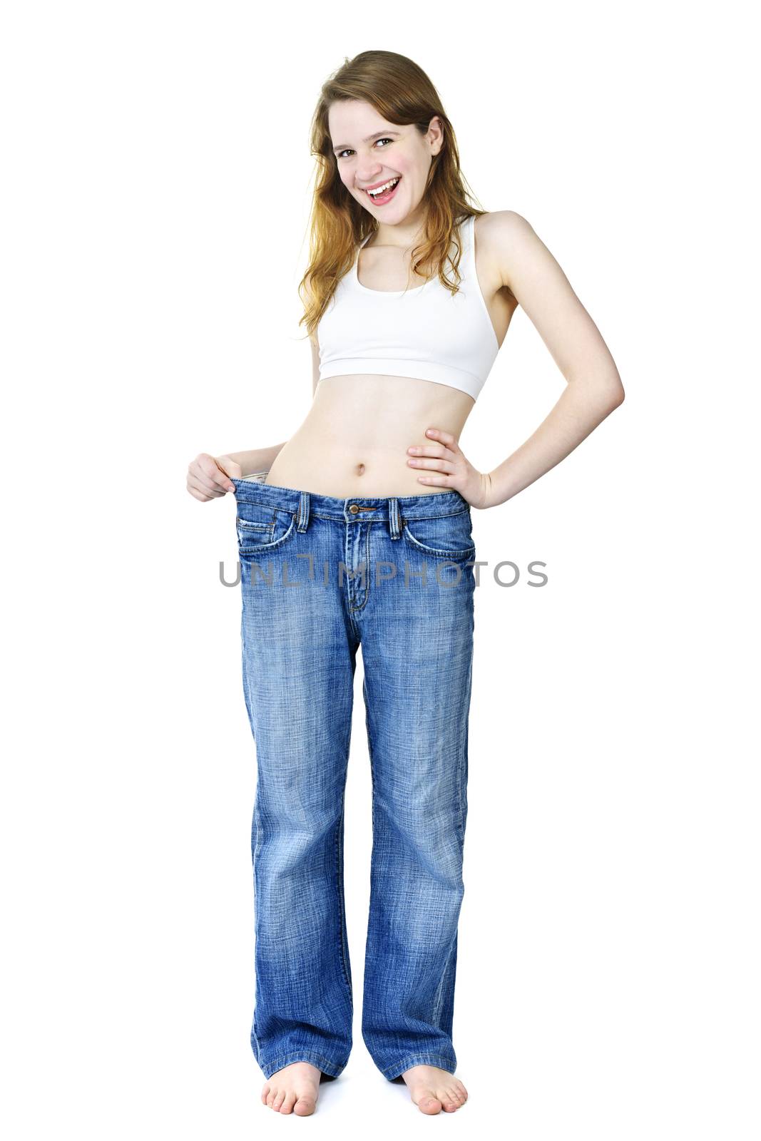 Happy fit young woman in loose old jeans after losing weight isolated on white