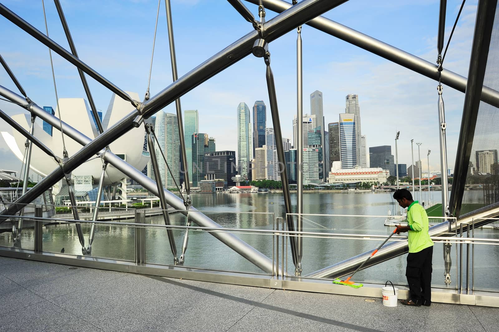 SINGAPORE- MAY 07, 2013: Worker cleaning the Helix bridge in front of Singapore downtown. The Helix is fabricated from 650 tonnes of Duplex Stainless Steel and 1000 tonnes of carbon steel.